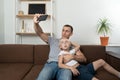 Young father taking selfie with his son sitting and making faces. Father and son having fun together Royalty Free Stock Photo