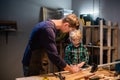 A young father teaches the basics of carpentry to his son in the garage. Royalty Free Stock Photo