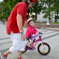 Young father teaching his daughter to ride a bike Royalty Free Stock Photo