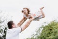 Young father throwing his baby daughter high in the sky in the park in summer day. father`s day Royalty Free Stock Photo