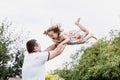 Young father throwing his baby daughter high in the sky in the park in summer day. father`s day Royalty Free Stock Photo