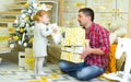 Young father and toddler daughter holding gift boxes near decorated Christmas tree at home Royalty Free Stock Photo