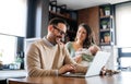 Young father works on laptop while his wife looks after child.Work from home parenting telecommuting Royalty Free Stock Photo