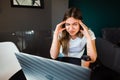 Young fatigued woman working at office desk in front of laptop, suffering from chronic daily headaches