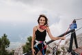 A young fearless woman in safety gear walks over a rope bridge over a precipice high in the mountains.