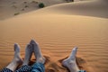 Young feet in the sand of Sahara Desert, Morocco. A couple sitting on the sand.
