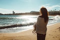 Young female adult standing in the sun next to the sea