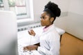 Young female African-american doctor working on modern ultrasound equipment. Operator of ultrasound scanning machine Royalty Free Stock Photo