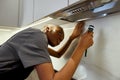 Female workman in grey t-shirt checking kitchen exhaust Royalty Free Stock Photo