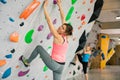 Young female alpinist practicing indoor rock-climbing on a artificial boulder without safety belts