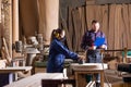 Young female apprentice polishing wood under senior colleague supervision Royalty Free Stock Photo