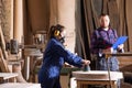 Young female apprentice polishing wood under senior colleague supervision Royalty Free Stock Photo