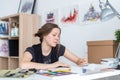 Young female artist drawing sketch using sketchbook with pencil at her workplace in studio. Side view portrait of Royalty Free Stock Photo