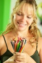 Young female artist looking at colored pencils and smiling Royalty Free Stock Photo