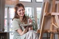 Young female artist works on abstract acrylic painting on canvas in art painting studio. Royalty Free Stock Photo