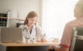 Young female Asian doctor smiling cheerfully talking to her patient during medical appointment communication interaction friendly