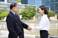 Young female Asian executive and senior Asian businessman shaking hands Royalty Free Stock Photo