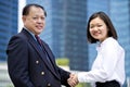 Young female Asian executive and senior Asian businessman shaking hands Royalty Free Stock Photo