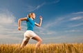 Young female athelte running across the field Royalty Free Stock Photo