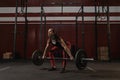 Young female athlete doing deadlift exercise. Strong woman lifting heavy barbell at crossfit gym Royalty Free Stock Photo