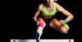 Young female athlete jumping over hurdle in sprint