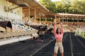 Young female athlete runner sitting on running track and stretching her legs, warming up. Royalty Free Stock Photo