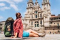 Young female backpacker piligrim sitting on the Obradeiro square plaza in Santiago de Compostela