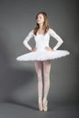 Young female ballet dancer tiptoeing against grey background Royalty Free Stock Photo