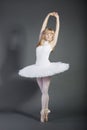 Young female ballet dancer tiptoeing over grey background Royalty Free Stock Photo