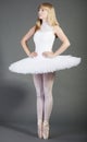 Young female ballet dancer in wearing tutu tiptoeing over grey background Royalty Free Stock Photo