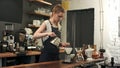 Young female barista in trendy modern cafe coffee shop pours boiling water over coffee grounds making a pour over drip