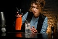 Female bartender holds orange siphon and accurate pours water from it Royalty Free Stock Photo