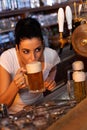 Young female bartender tasting draft beer