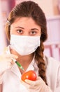 Young female biologist injecting syringe in a tomato