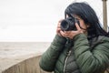 young female blogger content creator on a pier by the water taking photos with her digital camera Royalty Free Stock Photo