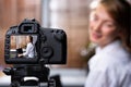 Young female blogger looking at camera and talking a video recording holding laptop at home. Social media blogger or content maker