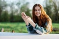 A young female blogger sits outdoors with her smartphone in hand and freelances in the outdoors. The concept of a