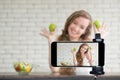 Young female blogger and vlogger and online influencer live streaming a cooking show on social media using a smartphone