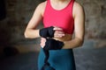 Young female boxer preparing for boxing fight. Athletic woman wearing strap on wrist before boxing practice in gym Royalty Free Stock Photo