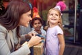 Young female brunette opening birthday presents to a little girl looking away