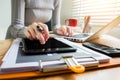 Young Female businessman or Designer using tablet with laptop and document on desk. Royalty Free Stock Photo