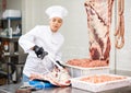 Young woman butcher sawing beef ribs