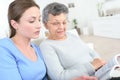 Young female caregiver reading story to old woman Royalty Free Stock Photo