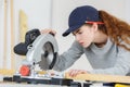 Young female carpenter using circular saw in workshop Royalty Free Stock Photo