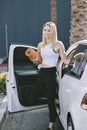 A Young Female Carrying a Yoga Mat Exits Her Car and is Happy