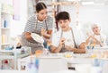 Young female ceramicist teaching guy to paint on ceramics in pottery studio Royalty Free Stock Photo