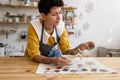 Young female ceramist in apron working in pottery studio, choosing paint color for ceramics goods Royalty Free Stock Photo