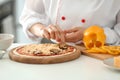 Young female chef cooking tasty pizza in kitchen, closeup Royalty Free Stock Photo