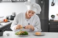 Young female chef preparing tasty salad in kitchen Royalty Free Stock Photo