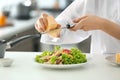 Young female chef preparing tasty salad in kitchen, closeup Royalty Free Stock Photo